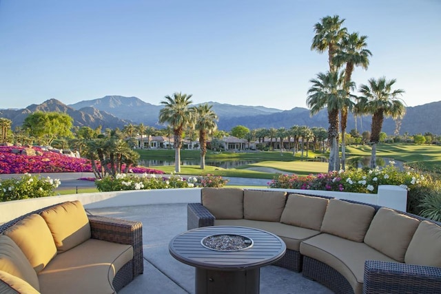 view of patio / terrace featuring a water and mountain view and an outdoor living space with a fire pit