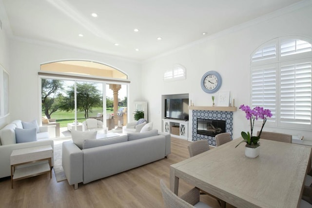 living room featuring crown molding, a tile fireplace, and light wood-type flooring