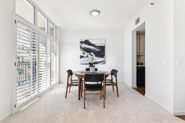 carpeted dining area featuring crown molding