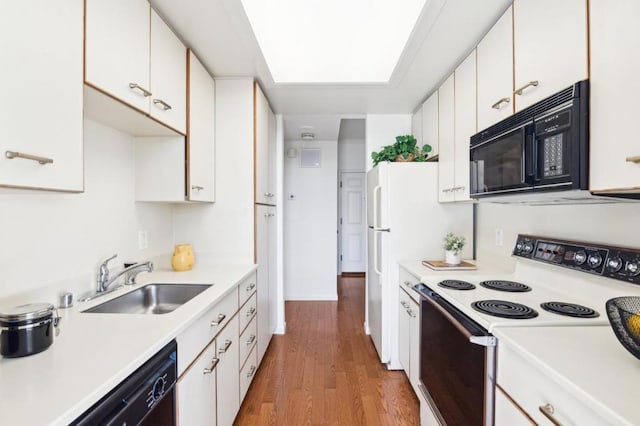 kitchen with black appliances, light hardwood / wood-style flooring, white cabinets, and sink