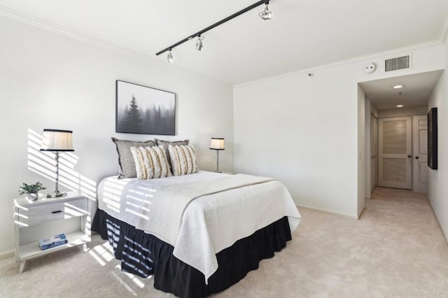 carpeted bedroom with crown molding and track lighting