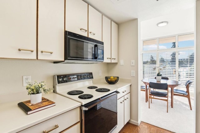 kitchen with light hardwood / wood-style floors, white cabinetry, and range with electric stovetop