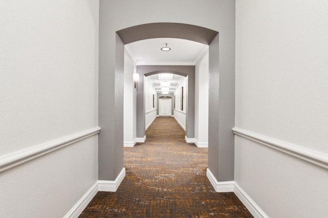 hallway featuring ornamental molding and dark colored carpet