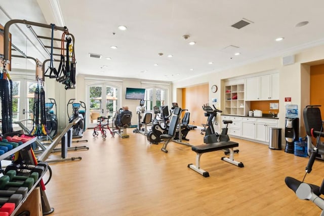 workout area with a wealth of natural light, ornamental molding, french doors, and light wood-type flooring