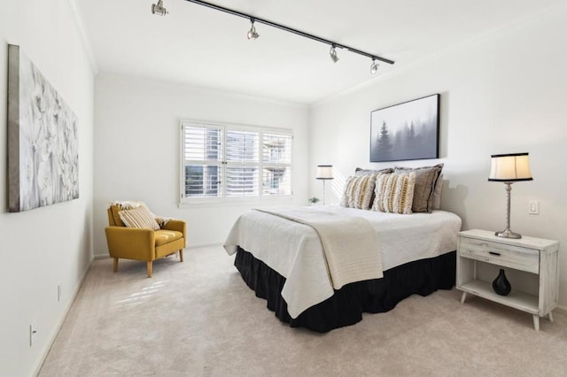 carpeted bedroom featuring track lighting and ornamental molding