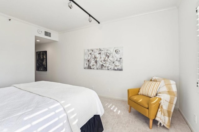 bedroom featuring track lighting, light colored carpet, and crown molding