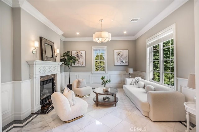 living room with a notable chandelier, a high end fireplace, and crown molding