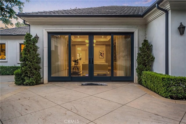 exterior entry at dusk featuring a patio area and french doors