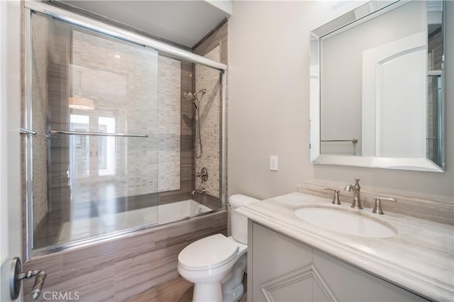 full bathroom featuring vanity, shower / bath combination with glass door, and toilet