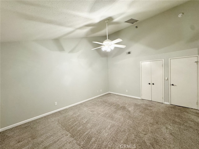 carpeted spare room featuring vaulted ceiling, ceiling fan, and a textured ceiling