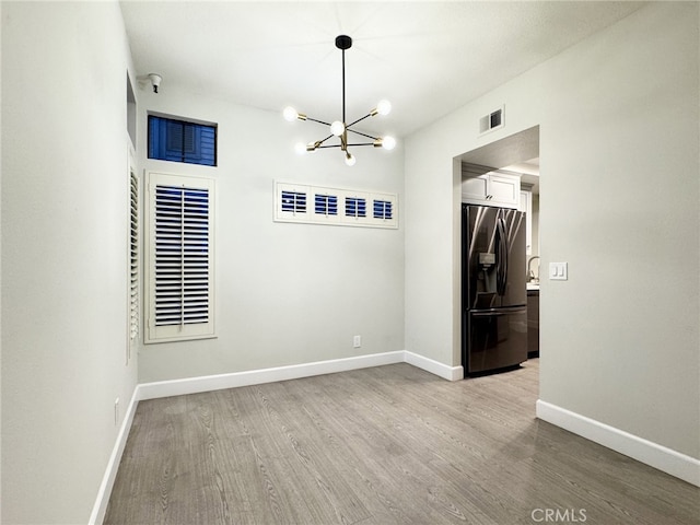 empty room featuring light hardwood / wood-style flooring and a notable chandelier