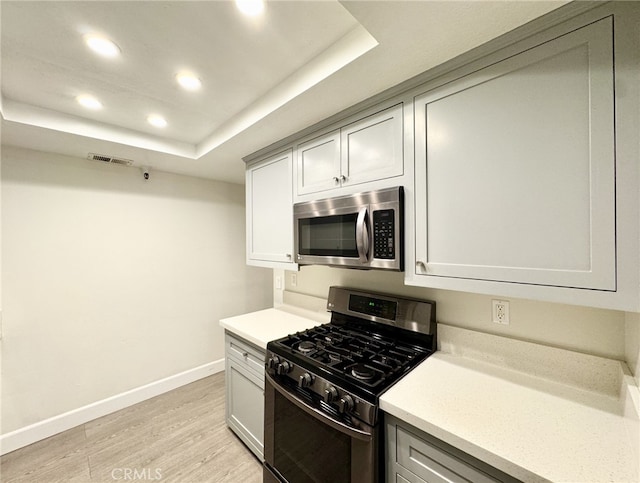 kitchen featuring light hardwood / wood-style floors, a raised ceiling, and range with gas stovetop