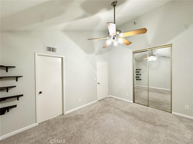 unfurnished bedroom featuring a closet, ceiling fan, vaulted ceiling, and carpet floors