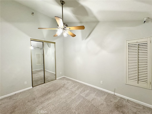 unfurnished bedroom with carpet, a closet, vaulted ceiling, and ceiling fan