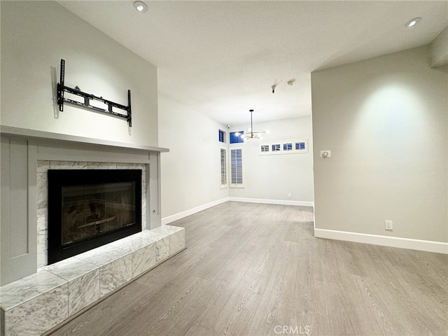 unfurnished living room featuring a fireplace, wood-type flooring, and a chandelier