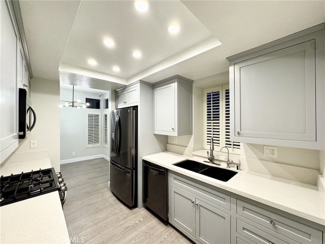 kitchen with black dishwasher, sink, refrigerator with ice dispenser, a raised ceiling, and stainless steel range with gas cooktop