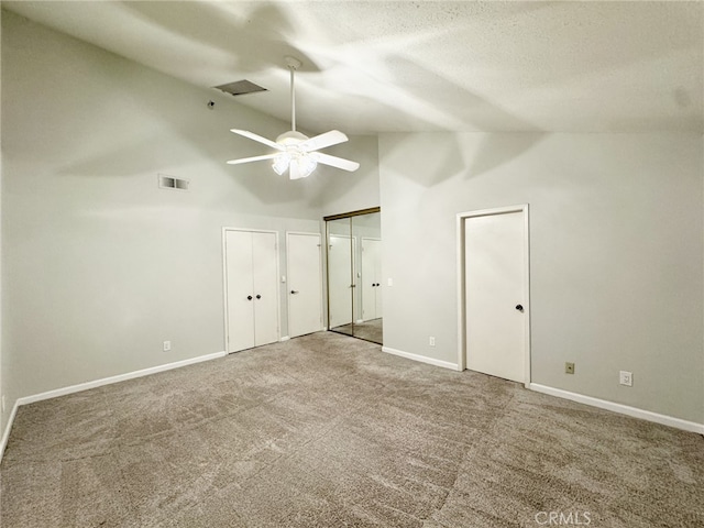 unfurnished bedroom with ceiling fan, two closets, carpet, and high vaulted ceiling