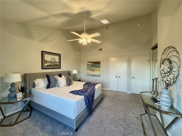 bedroom with visible vents, baseboards, carpet, high vaulted ceiling, and multiple closets