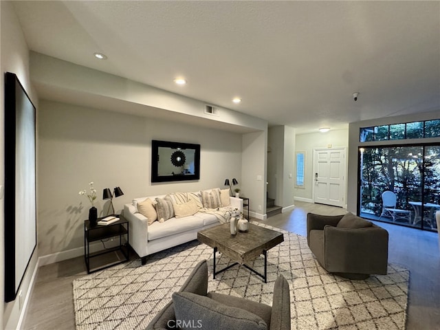 living room with recessed lighting, visible vents, baseboards, and wood finished floors