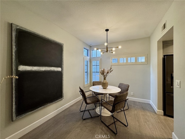 dining area featuring an inviting chandelier, visible vents, baseboards, and wood finished floors