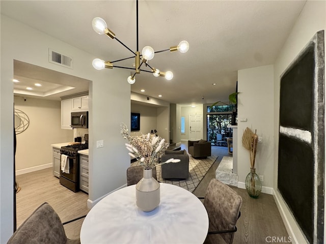 dining room featuring light wood-style floors, baseboards, visible vents, and recessed lighting