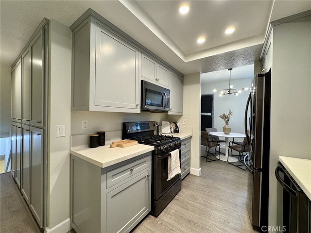 kitchen featuring recessed lighting, light countertops, black appliances, light wood finished floors, and decorative light fixtures