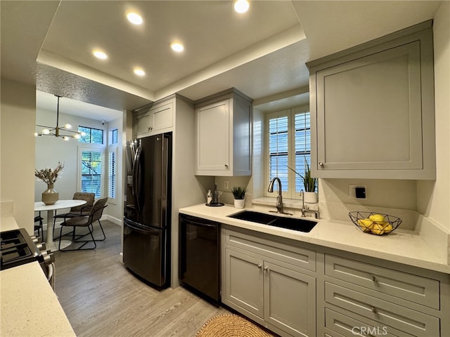 kitchen with gray cabinets, a raised ceiling, a sink, and black appliances