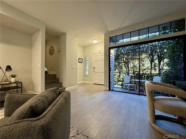 living room featuring stairway, baseboards, and wood finished floors