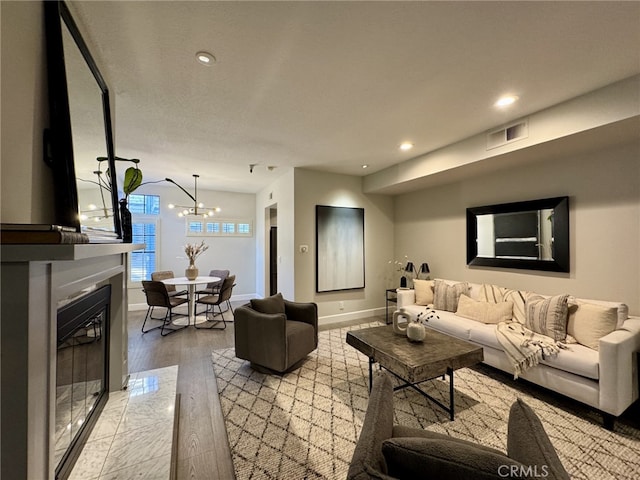 living room with a fireplace with flush hearth, recessed lighting, visible vents, and baseboards