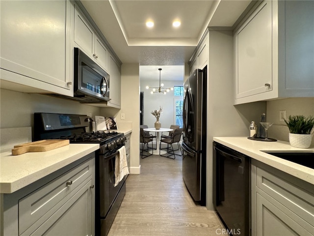 kitchen featuring black appliances, pendant lighting, light countertops, and light wood-style floors