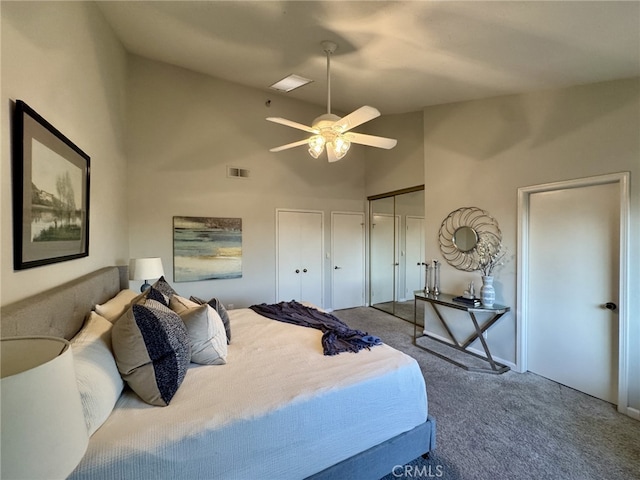 carpeted bedroom featuring multiple closets, visible vents, high vaulted ceiling, and a ceiling fan