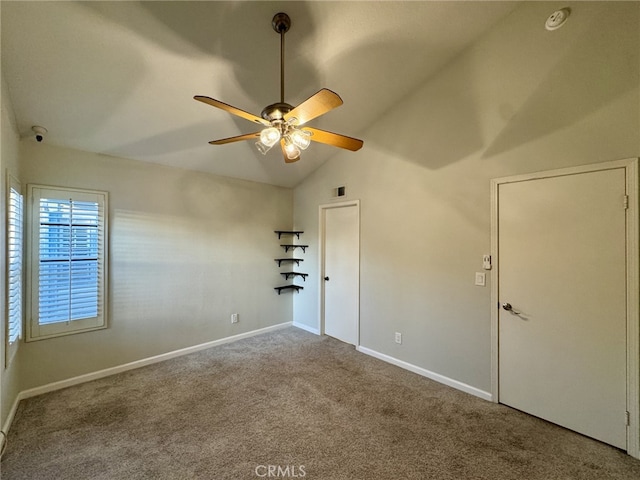 empty room with lofted ceiling, carpet floors, a ceiling fan, and baseboards