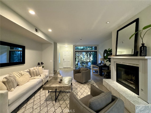 living room with recessed lighting, a premium fireplace, visible vents, baseboards, and light wood-style floors