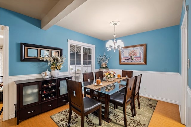 dining area featuring a chandelier, beamed ceiling, and light hardwood / wood-style floors