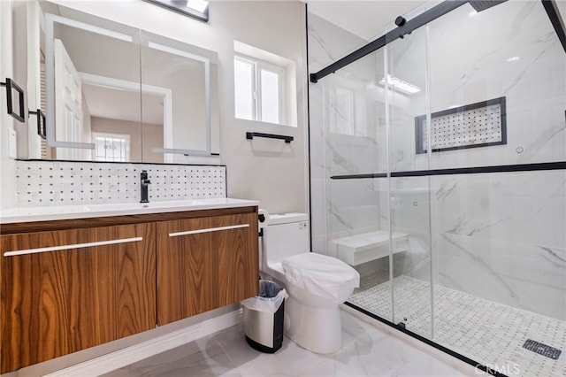 bathroom featuring a shower with door, toilet, vanity, and tasteful backsplash