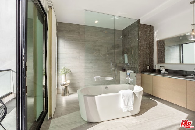 bathroom featuring vanity, plus walk in shower, tile patterned flooring, and tile walls