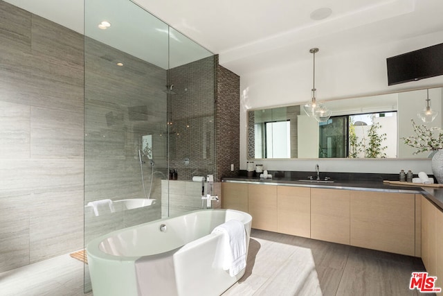 bathroom with vanity, shower with separate bathtub, and tile walls