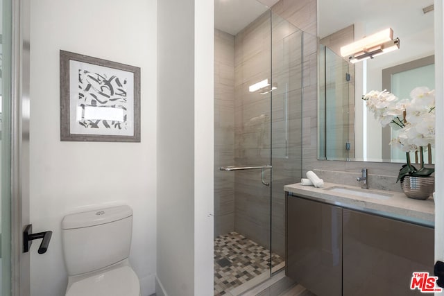 bathroom featuring vanity, a shower with door, and toilet