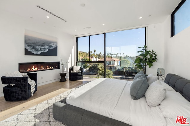 bedroom with multiple windows, a wall of windows, and light hardwood / wood-style flooring