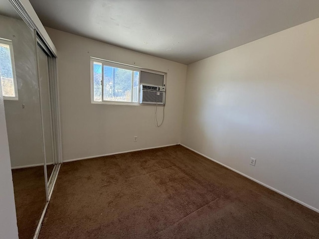 unfurnished bedroom featuring a closet, cooling unit, and dark carpet