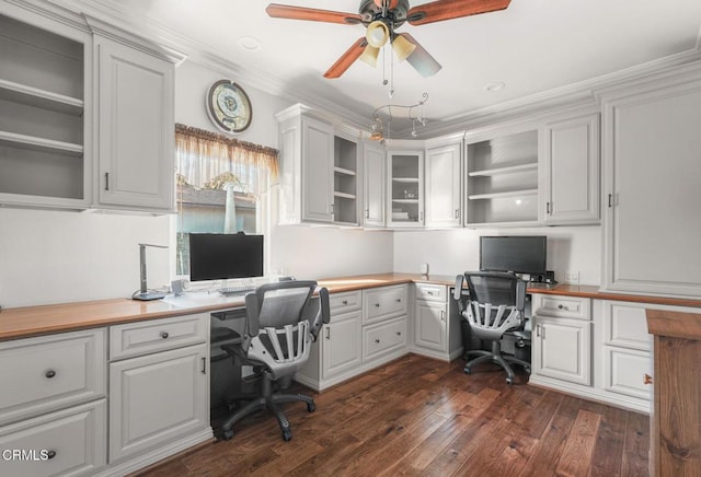 office space featuring crown molding, dark wood-type flooring, built in desk, and ceiling fan