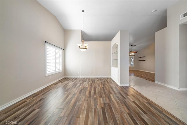 interior space with ceiling fan with notable chandelier, built in shelves, lofted ceiling, and hardwood / wood-style floors