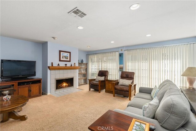 living room featuring light carpet and a tiled fireplace