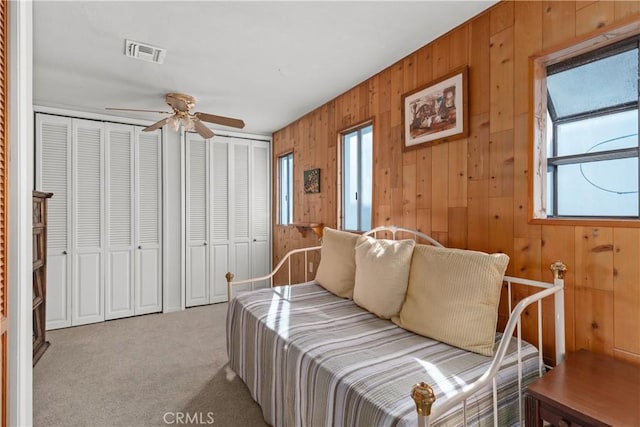 bedroom with multiple closets, light colored carpet, and ceiling fan