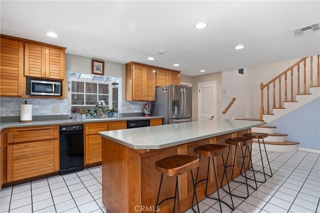 kitchen featuring a center island, light tile patterned floors, decorative backsplash, a breakfast bar, and stainless steel appliances