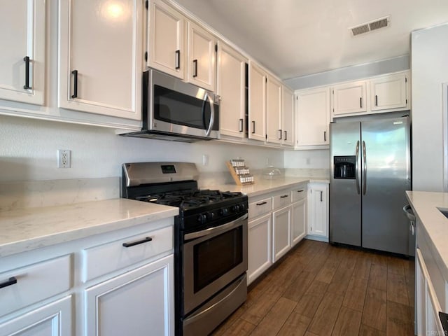 kitchen featuring white cabinets, dark hardwood / wood-style floors, light stone countertops, and appliances with stainless steel finishes