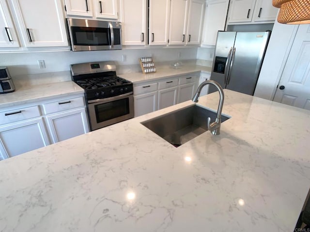 kitchen with light stone counters, sink, white cabinets, and stainless steel appliances