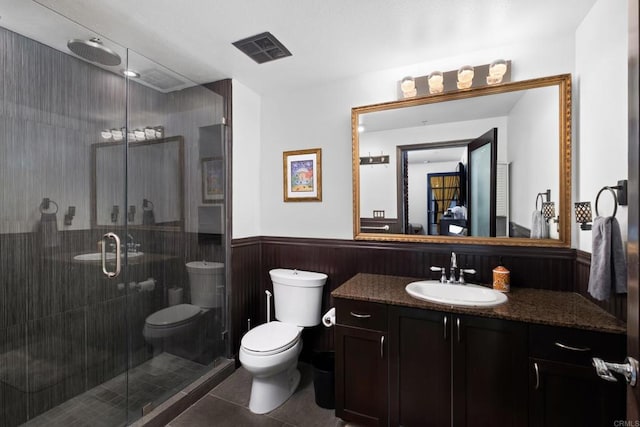 bathroom with walk in shower, vanity, tile patterned floors, and toilet