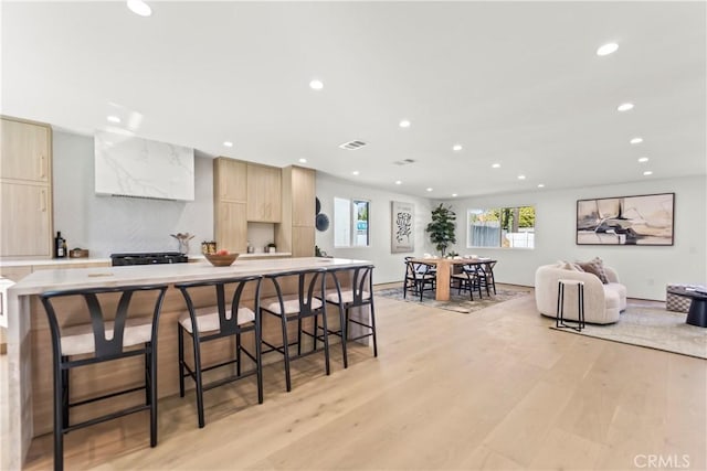 kitchen featuring a kitchen island, light hardwood / wood-style floors, a breakfast bar, and light brown cabinets