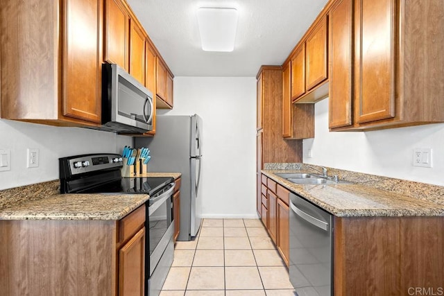 kitchen with light stone counters, sink, appliances with stainless steel finishes, and light tile patterned flooring